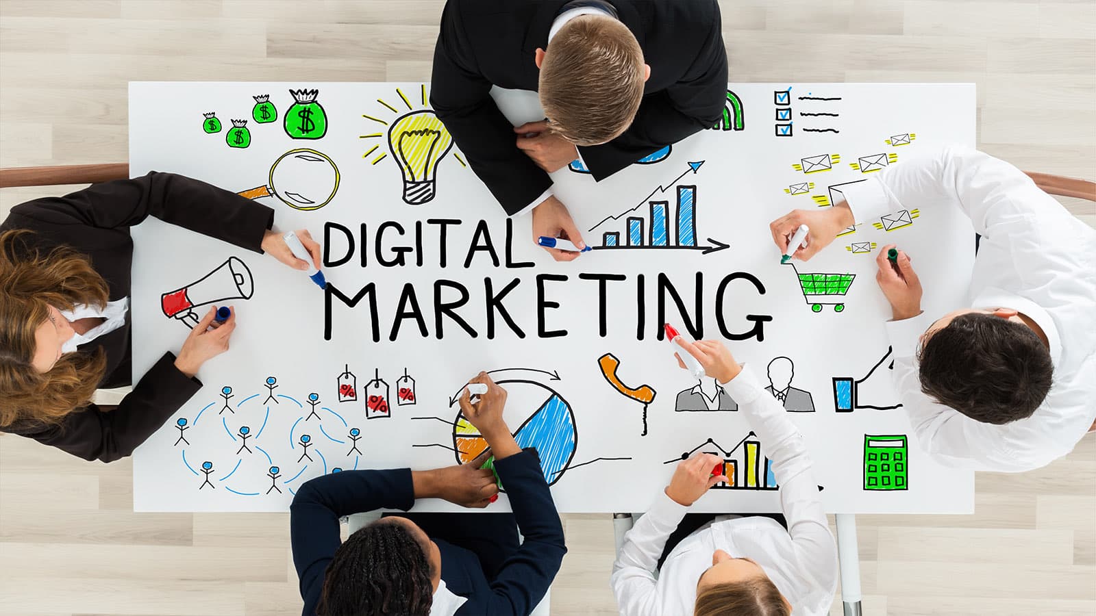 A team around a table covered in hand-drawn digital marketing icons and the words 'Digital Marketing'